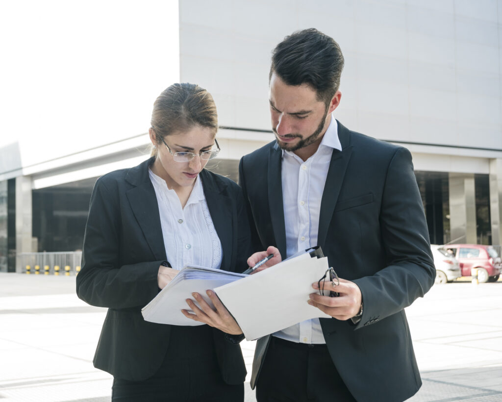 businessman businesswoman checking documents outdoors