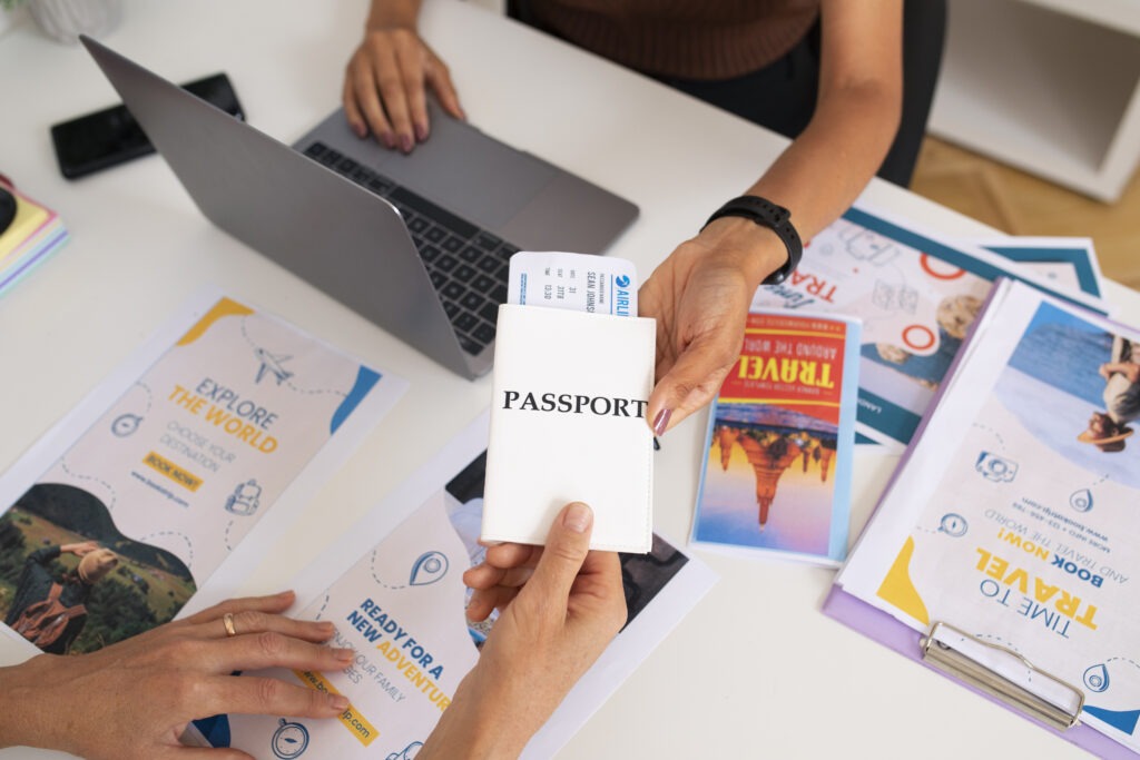 high angle travel agency desk with people working laptop holding passport